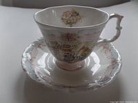 Side view of the Royal Doulton Brambly Hedge tea cup on matching saucer, showing detailed colored wedding scene illustration and floral border pattern.