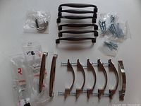 Overview photo of all drawer pulls shown together on a white surface, black, chrome, and brushed nickel finishes visible.