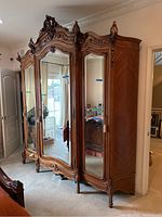 Front view of armoire showing three mirrored doors and ornate carvings