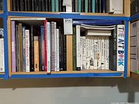 Bookshelf containing assorted art books from various art periods and styles, showing titles and spines of books in detail.
