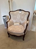 Front view of wingback armchair showing wood frame, floral upholstered fabric, and decorative pillow.