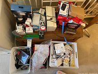 Overview of bench top showing boxed Vivitar and Wahl kits, RokBlok box, bins of cables and small electronics