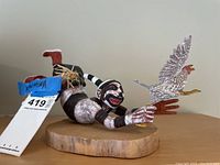 Full side view of carved polychrome Kachina figurine on round wood base