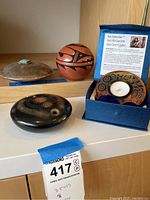 Overview of three items: red pot, black pot, and Wade Baker candle holder