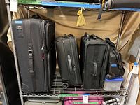 Full view of all four suitcases including one large, two medium, and one small carry-on on metal shelf.