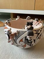 Overall view of bowl showing geometric designs and multiple attached child figurines climbing the rim