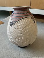 Front view showing carved relief of stylized bird and geometric pattern with painted neck band