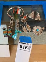 Overview of cuff, earrings and pendants on glass surface
