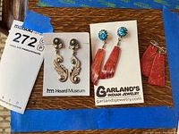 Lot of three pairs of Native American style earrings displayed on a wooden surface with parts of the packaging and labels visible.