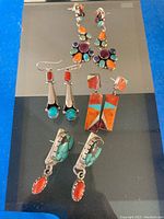 Four pairs displayed on mirror: chandelier, coral/turquoise drop, rectangular inlay and turquoise/coral drop earrings