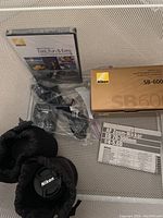 Overview of Nikon SB-600 flash box, DVD, sealed charger bag, AF Zoom-Nikkor manual, lens pouch with cap