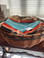 Round cane basket with folded Pendleton textiles inside