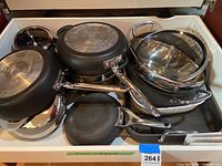 Top view of wide assortment of pots and pans, some with metal or glass lids, showing condition and type.