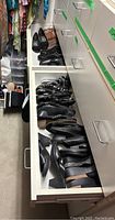 Two drawers open in closet showing assorted shoes in both compartments