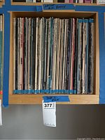 Wooden shelf holding approximately 40 vinyl record spines under label 'Blue Rock'.