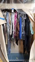 Full rack view showing garments on hangers under plastic covers in wardrobe