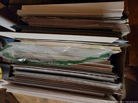 Stack of various 12" x 12" papers including pads and loose sheets, some still in plastic bags.
