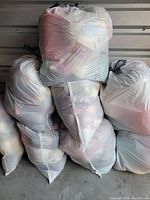 Stack of eight large white plastic bags filled with yarn of various colors and textures.