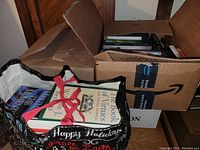 Photo showing two boxes and a tote bag filled with books, partially visible titles with motivational and spiritual themes.