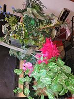Top view of artificial flower arrangements showing various types of leaves and flowers including pink blooms.