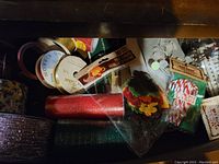 Photo showing various Christmas craft supplies including rolls of glitter ribbon, packs of felt decorations, candy cane pieces, and decorative tape.