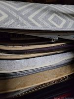 Close view of stacked carpet samples showing edges and textures in gray, beige and purple tones.