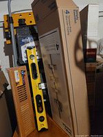 Photo showing yellow Cosco folding workbench, yellow spirit level, boxed shower caddy, two wooden slatted panels, and metal folding step stool with handle.