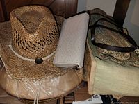 View of two straw hats, off-white wallet, and two burlap purses including one tote style with brown handles showing their condition and materials