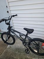 Side view of black Mike Spinner kids BMX bike showing scratches and wear on the frame, handlebars, and seat.