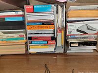 Photo showing stacked sealed paper products including envelopes, labels, photo papers, and colored paper pads.