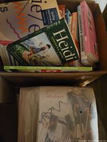 Box containing several paperback books including 'Heidi' and other literature, some visible on top.
