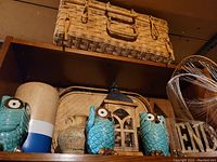 Decorative blue owl figurines, rustic ceramic vases, wooden lantern, and a woven basket on a shelf