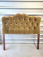 Full view of vintage velvet twin headboard showing the olive velvet upholstery, button tufting in diamond pattern, and wooden legs with mounting holes.