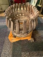 Close-up front view of the cast iron fireplace basket showing vertical bars with circular holes and overall structure.