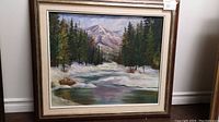 Front view of framed painting showing the full artwork depicting a snowy landscape with trees and mountains.