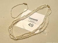 Set showing the triple-strand pearl choker necklace laid flat with the single-strand pearl bracelet beside it, both pearls are white and irregularly shaped, clasps visible.