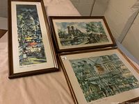 Three framed prints arranged on table, showing vintage Paris scenes including Saint Paul, Notre Dame, and Moulin Rouge.