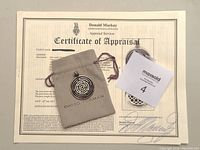 Pendant, pouch and certificate of appraisal laid out together