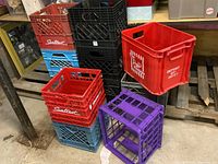 Overall view of stacked dairy-style crates including red, blue, black, purple, and a Pop Shoppe crate.