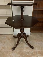 Front view of the two-tier mahogany table showing the octagonal tops, central turned pedestal and four splayed carved claw feet.