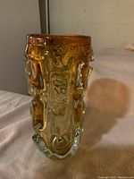 Side view of textured clear to amber glass vase showing sculptural, organic raised patterns and thick base.