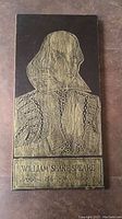 Full view of wood panel illustrating William Shakespeare in an etching style with inscription.