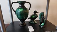 Full view of the three pottery items including the large vase, duck figurine, and swan vase arranged on a shelf.