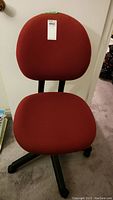 Front view of red upholstered computer chair with curved backrest and padded seat