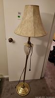 Full view of floor lamp showing brass base, crystal accent, and beige fabric shade.