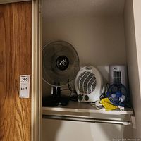 Three fans on a shelf: a Fusion oscillating table fan, a Fusion electric fan heater, and a small blue Comfort Zone USB fan.