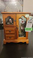 Front view of the wooden jewellery box showing floral glass panels, drawers, and door with metal latch