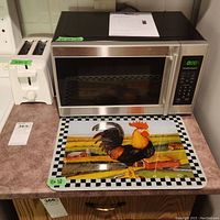 Microwave, toaster, and rooster cutting board displayed together on countertop