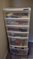 Overall view of five-drawer plastic storage filled with sewing notions including thread, buttons, and trims.