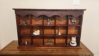 Front view of wooden shelf with miniatures in cubbies showing overall arrangement and items included